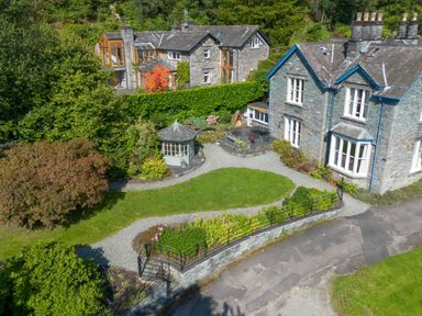 A stone house with a garden path a small gazebo and trees at Stepping Stones House in Ambleside