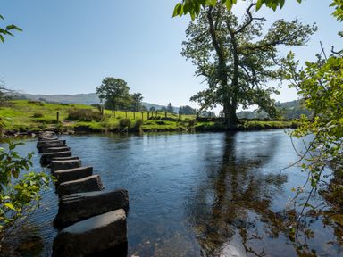 A river with stepping stones leading across and trees on the riverbank at Stepping Stones House in Ambleside