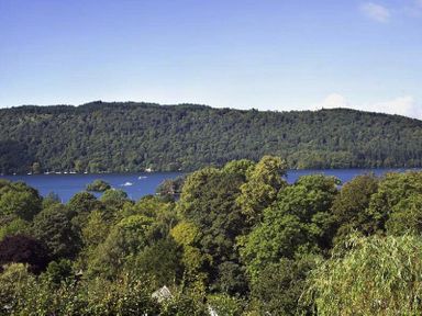 A landscape with trees in the foreground a lake and hills in the background at Primrose Mount in Bowness