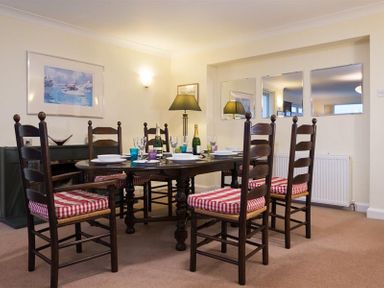 A dining room with a dark wooden table and six chairs with red and white striped cushions at Primrose Mount in Bowness