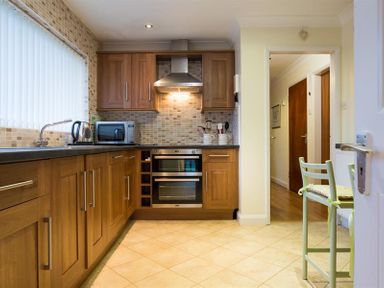 A kitchen with wooden cabinets a microwave kettle sink and stove at Primrose Mount in Bowness