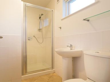 A bathroom with a shower enclosure a pedestal sink and a toilet at Primrose Mount in Bowness