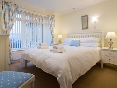 A bedroom with a bed with stacked towels and a bedside table with lamps at Primrose Mount in Bowness