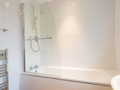 A bathroom with a bathtub shower combo with glass screen and towel holder at Primrose Mount in Bowness