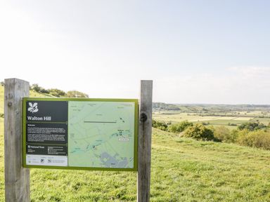 A wooden post sign with a map of Walton Hill and a landscape view of fields and trees at Old Cary Cottage in Henley near Langport