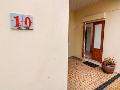 The entrance to a house with an open wooden door a potted plant a doormat and the number 10 on the wall at St Julien in Dawlish
