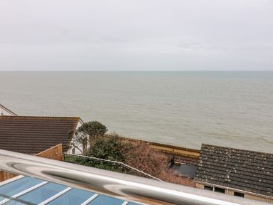 A view of the sea with rooftops and vegetation in the foreground at St Julien in Dawlish