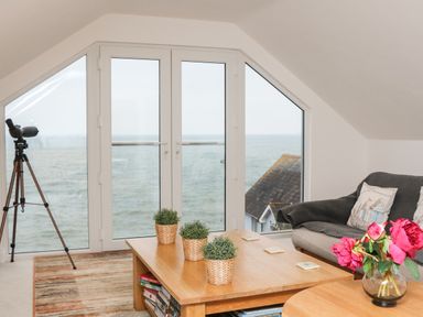 A sitting area with a telescope near glass doors overlooking the sea at St Julien in Dawlish