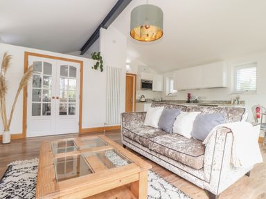 A living room with a sofa and coffee table near a kitchen at Chycoose in Hicks Mill near Perranarworthal