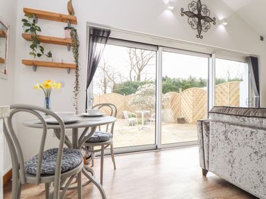 A dining area with a small round table and two chairs near sliding glass doors opening to a patio at Chycoose in Hicks Mill near Perranarworthal
