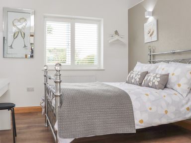 A bedroom with a metal bed frame and floral bedding with three cushions at Chycoose in Hicks Mill near Perranarworthal