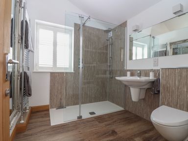 A bathroom with a walk-in shower a wall-mounted sink a toilet towels and a large mirror at Chycoose in Hicks Mill near Perranarworthal