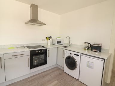A kitchen with an oven stove microwave washing machine and fridge at Coolnaharragill Lower Annexe in Glenbeigh County Kerry