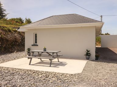 An outdoor area with a picnic table and potted plants next to a small building at Coolnaharragill Lower Annexe in Glenbeigh County Kerry