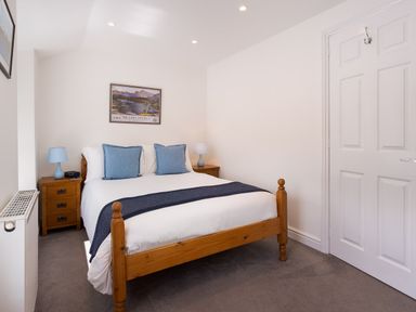 A bedroom with a wooden bed blue pillows bedside tables and lamps at Fern Cottage Ambleside