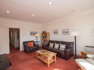 A living room with brown leather sofas a wooden coffee table bookshelf and floor lamps at Romney 12 Waterhead near Ambleside