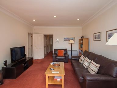 A living room with leather sofas a coffee table a television and a bookshelf at Romney 12 Waterhead near Ambleside