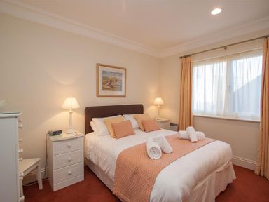 A bedroom with a double bed two bedside tables lamps a window with curtains and a chest of drawers at Romney 12 in Waterhead near Ambleside