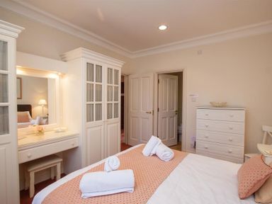 A bedroom with a bed with folded towels a vanity table a wardrobe and a chest of drawers at Romney 12 in Waterhead near Ambleside