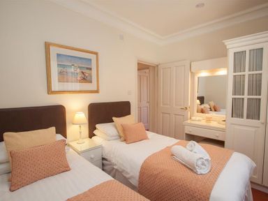 A bedroom with two single beds bedside table lamp dresser with mirror and wardrobe at Romney 12 Waterhead near Ambleside