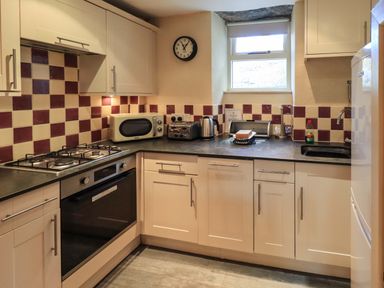 A kitchen with appliances and checkered wall tiles at Penny Red Cottage in Ambleside