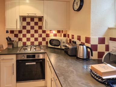 A kitchen countertop with a stove oven microwave toaster and kettle at Penny Red Cottage in Ambleside