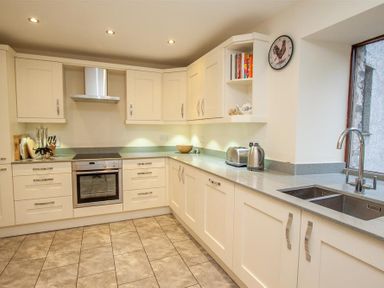 A kitchen with cream cabinets stainless steel appliances a double sink and a window at The Miller in Ambleside
