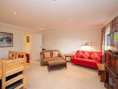 A living room with a red sofa wooden chairs and a television at The Miller in Ambleside