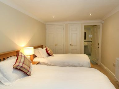 A bedroom with two single beds a lamp on a bedside table and three doors at The Miller in Ambleside