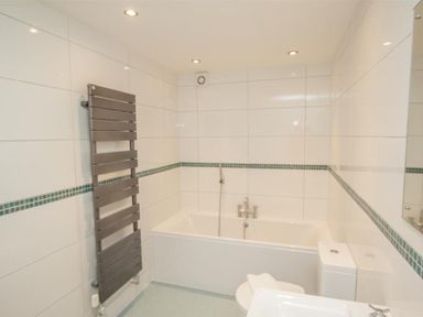 A bathroom with a bathtub toilet and heated towel rail at The Miller in Ambleside