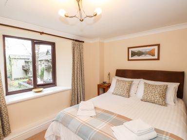 A bedroom with a double bed pillows and folded towels on the bed next to a window with curtains at Waterfalls Ambleside