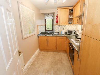 A kitchen with wooden cabinets oven microwave sink and a window at Waterfalls in Ambleside