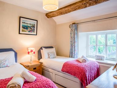 A bedroom with two single beds and a wooden nightstand with a lamp at Knotts Cottage in Troutbeck
