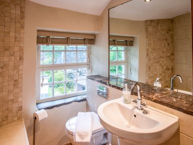 A bathroom with a sink toilet window and mirror at Knotts Cottage in Troutbeck