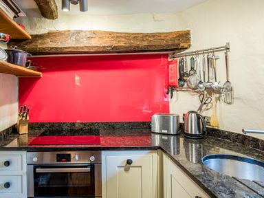 A kitchen with electric stove oven knife block toaster kettle and hanging utensils at Knotts Cottage in Troutbeck