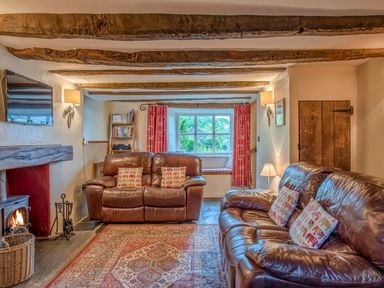 A living room with leather sofas and a fireplace at Knotts Cottage in Troutbeck