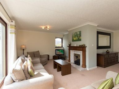 A living room with sofas a fireplace a television and a wooden cabinet at Todd Crag in Ambleside