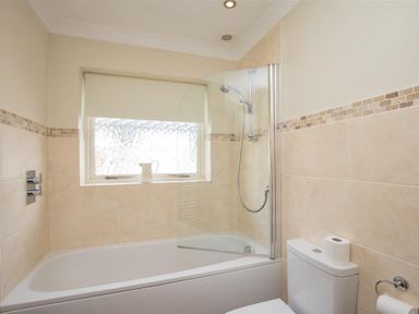A bathroom with a bathtub shower combination window and a toilet with toilet paper at Todd Crag Ambleside