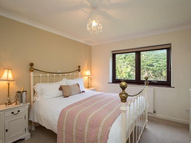 A bedroom with a double bed pillows bedside tables lamps and a window showing trees at Todd Crag in Ambleside