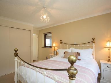 A bedroom with a white metal bed, bedside tables with lamps, and a window at Todd Crag in Ambleside