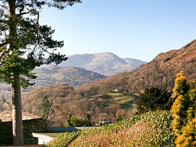 A landscape view of hills and trees with a clear sky at Todd Crag in Ambleside