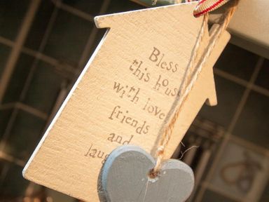 A wooden house-shaped decoration with text and a hanging gray heart at Sunset Cottage in Ambleside