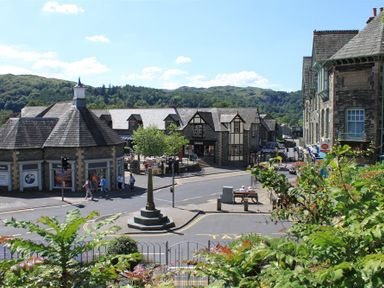 A street view with stone buildings a monument and people walking in Ambleside