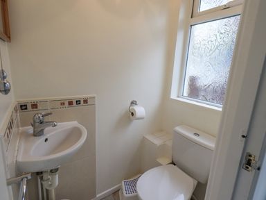 A small bathroom with a toilet sink small step stool and frosted window at Fellcroft in Troutbeck