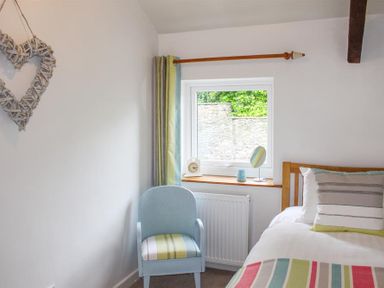 A bedroom with a single bed next to a window and a blue chair at Four Seasons Cottage in Ambleside