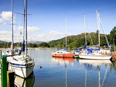 Sailboats docked on a lake with hills and trees in the background at Four Seasons Cottage in Ambleside