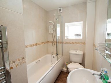 A bathroom with a bathtub shower toilet and sink at Acorn Cottage in Ambleside