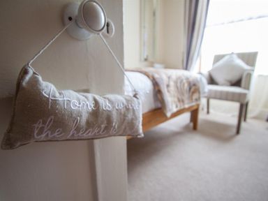 A bedroom with a bed covered with a blanket and a chair by the window at Acorn Cottage in Ambleside