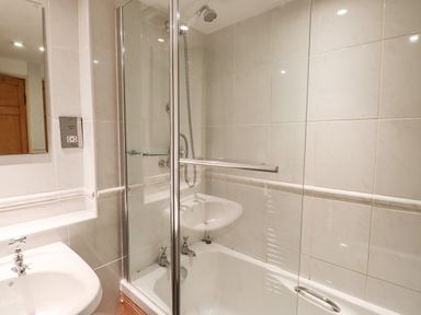 A bathroom with a bathtub shower combination and a sink at Rock Cottage in Ambleside