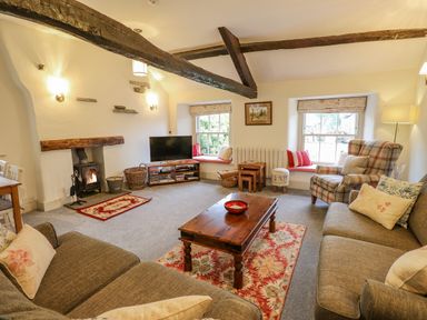 A living room with sofas a coffee table a fireplace and windows with cushions at Highfold Ambleside
